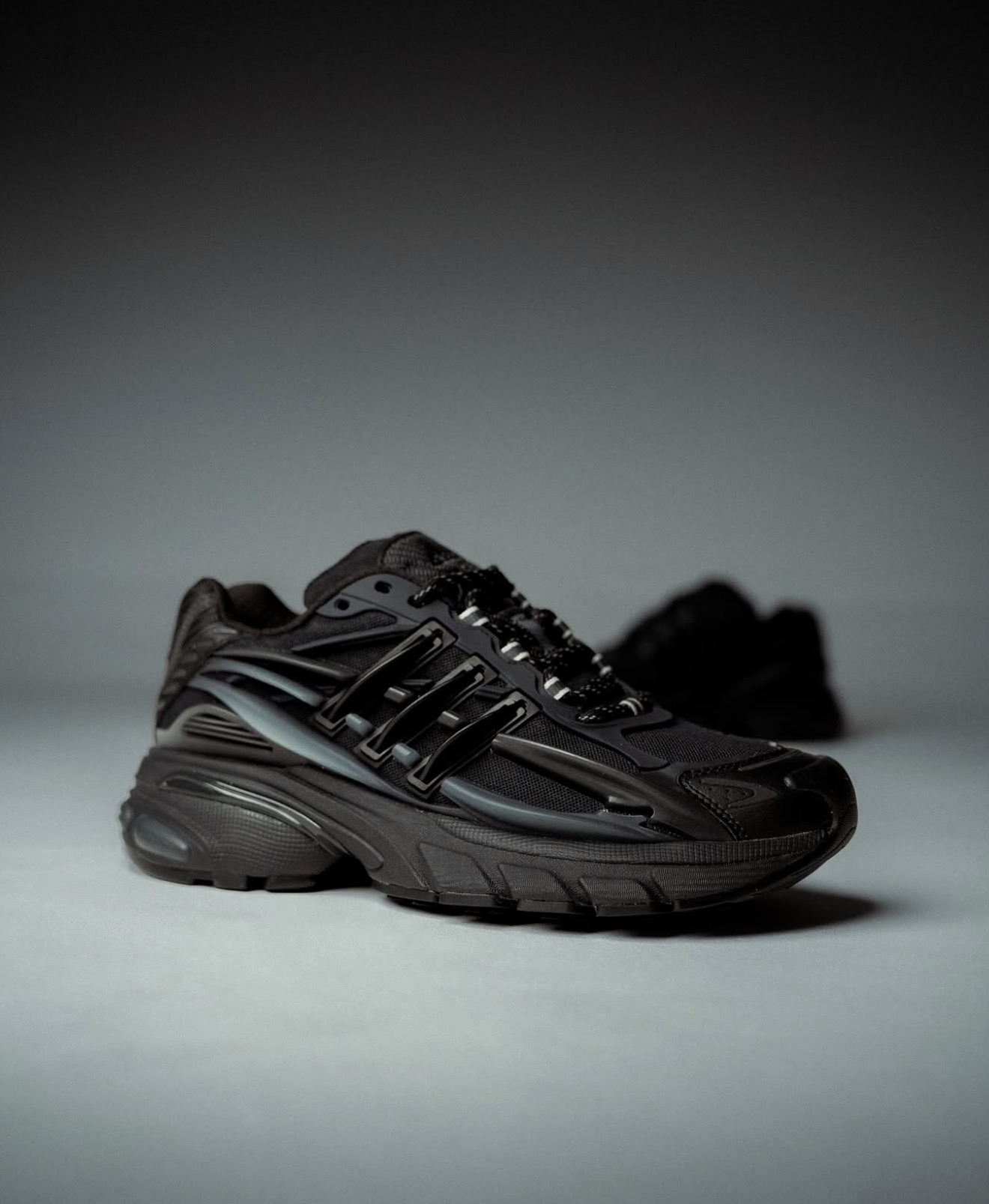 All-black adidas runner photographed in studio light — Holy Grail