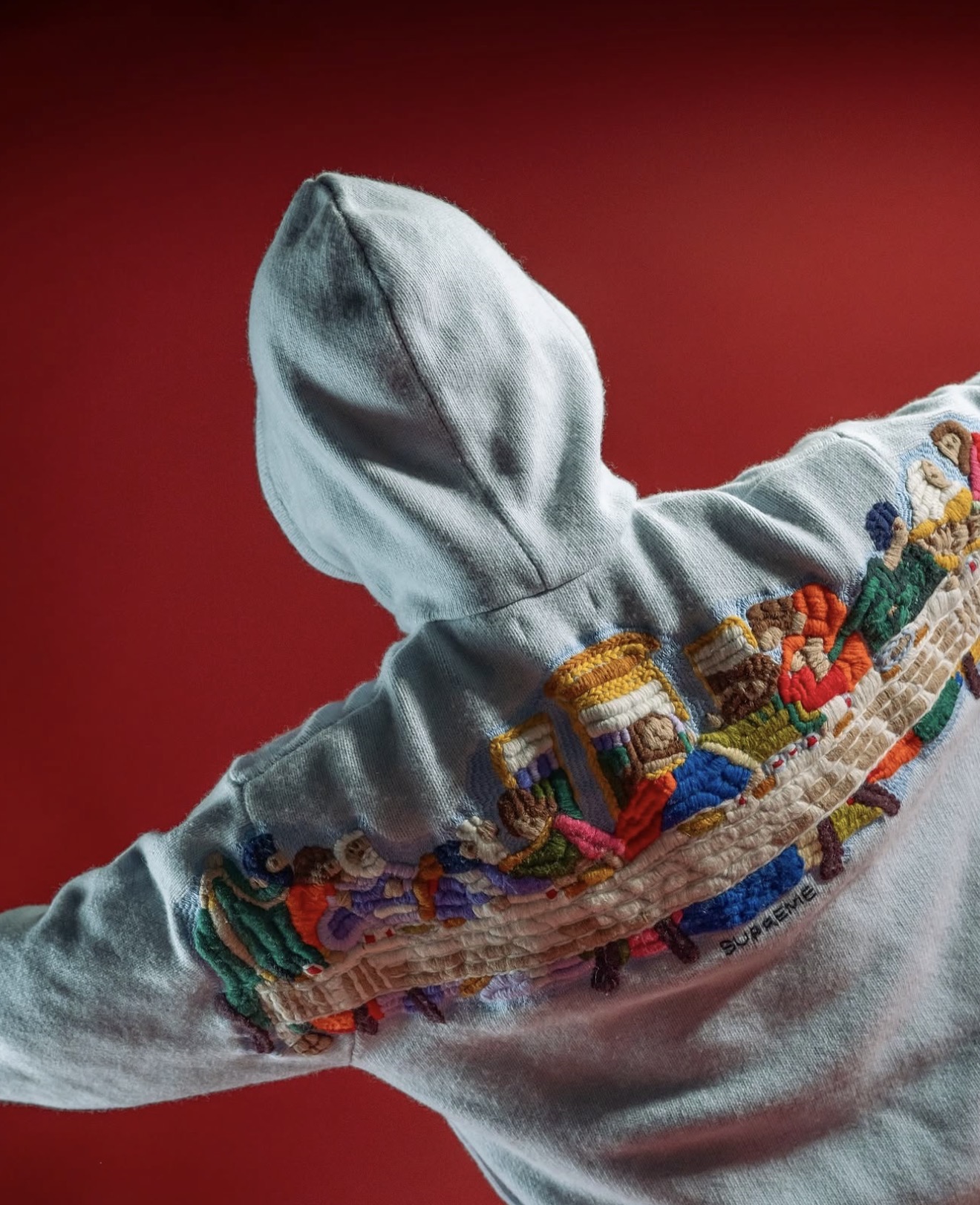 Grey Supreme hoodie with colourful embroidery on a red backdrop — Holy Grail