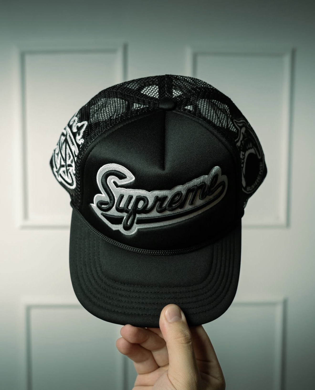 Black Supreme mesh trucker cap held in hand — Holy Grail