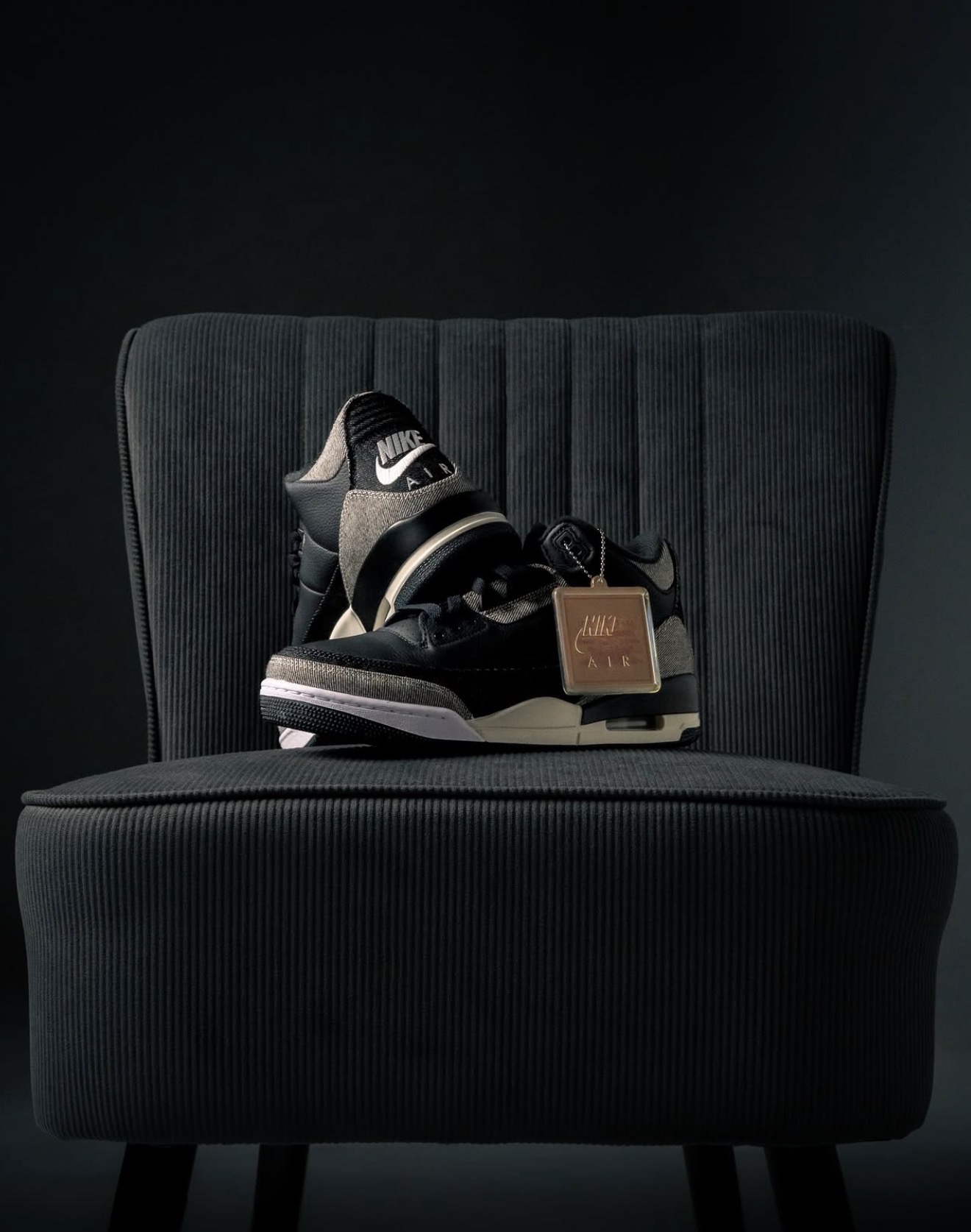 Black Nike Air high-top with hangtag on a dark corduroy chair — Holy Grail