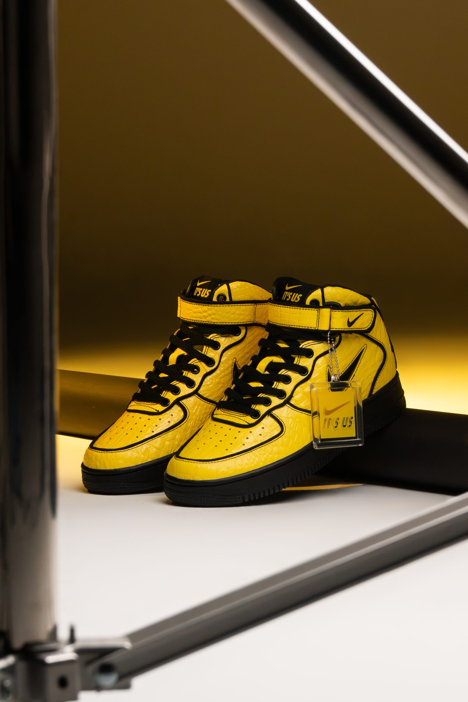 Par de Nike Air Force 1 Mid x Lil Yachty Opti Yellow fotografiado en estudio, mostrando su diseño amarillo y negro con detalles exclusivos.